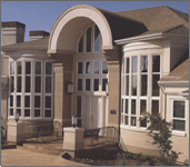 Picture of a front of a house with a lot of nicely designed windows.